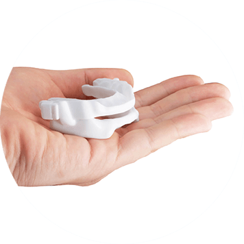 A person holding a white custom-made oral appliance in their palm.